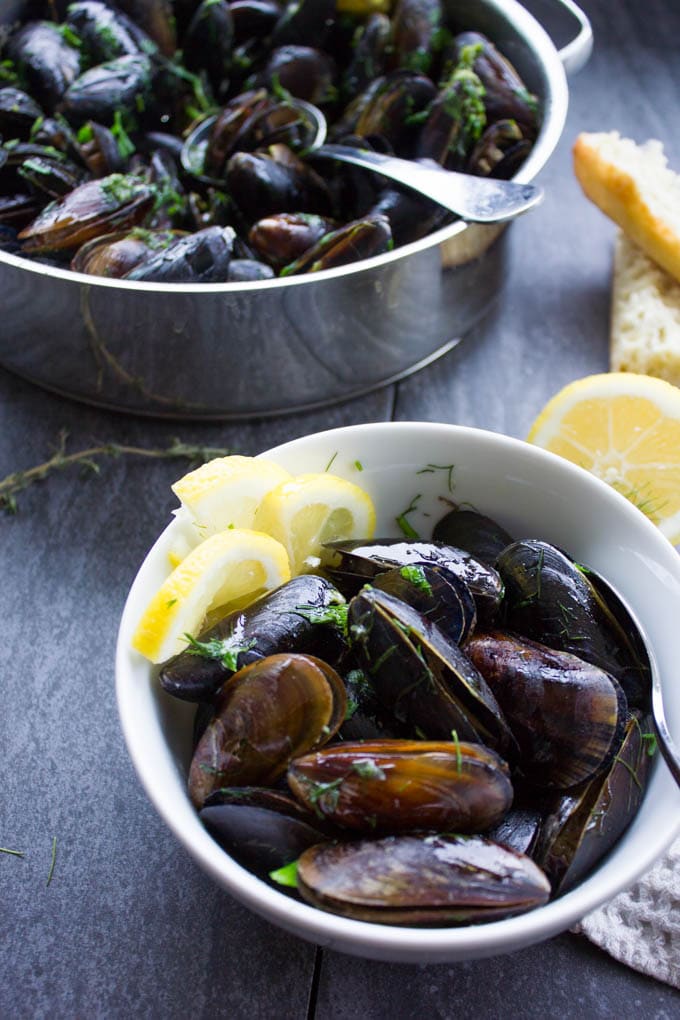 One bowl with lemon slices and mussels cooked.