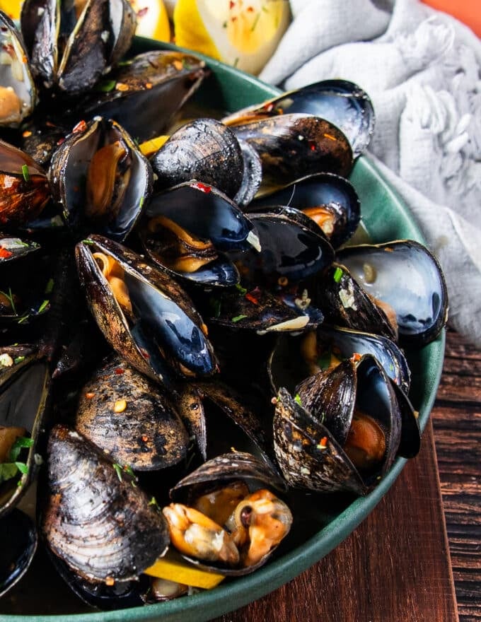 half a plate of mussels cooked in garlic and lemon with a saucy broth