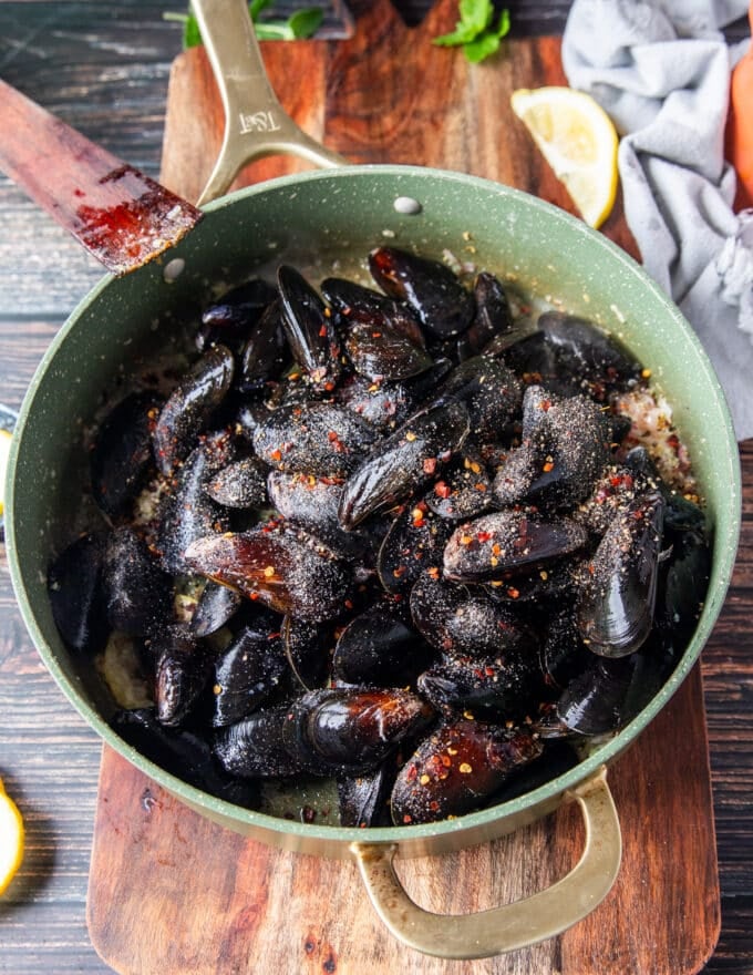 raw mussels added in a pot and seasoned