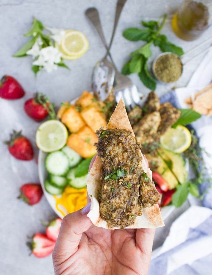 a wedge of pita bread topped with a piece of Zaatar Chicken