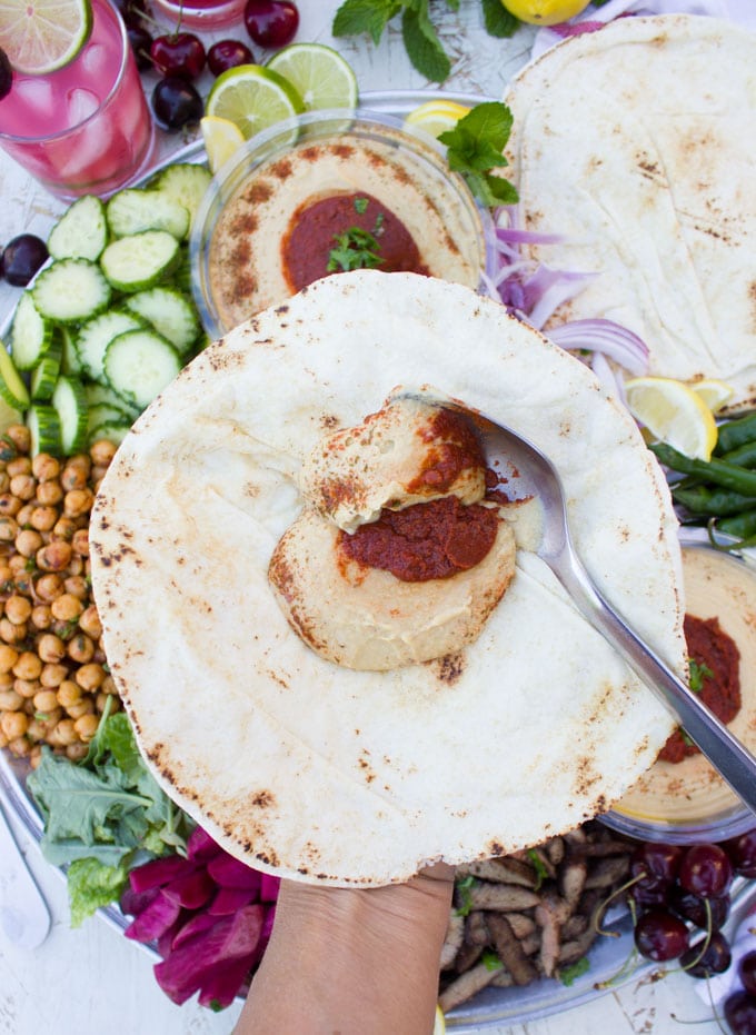 Spreading the hummus on a pita bread