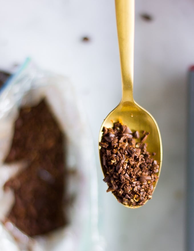 a spoon holding over the crushed coffee beans to show the texture needed for the ground coffee beans