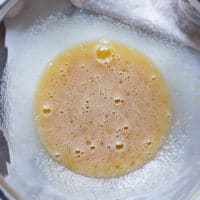 A bowl with eggs and sugar whisked together to make the chewy coffee cookies