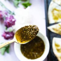 a spoon showing off moroccan olive oil blended with zaatar in a bowl