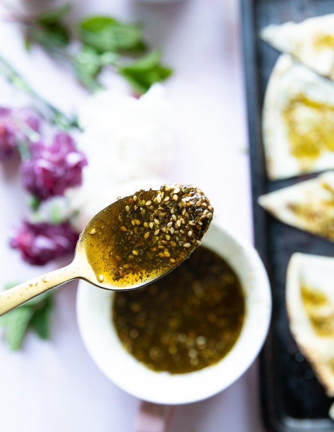 a spoon showing off moroccan olive oil blended with zaatar in a bowl