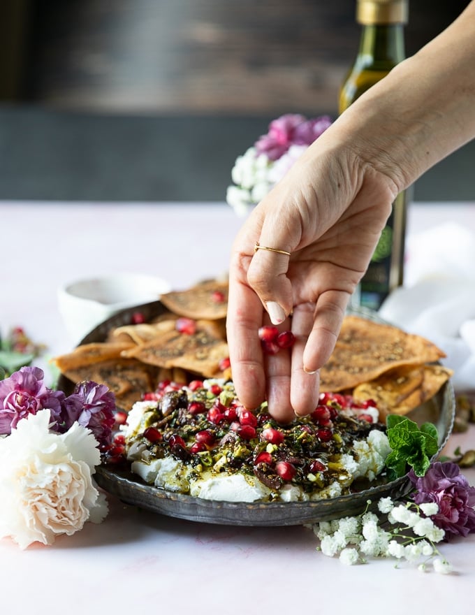 A hand sprinkling some pomegranate seeds