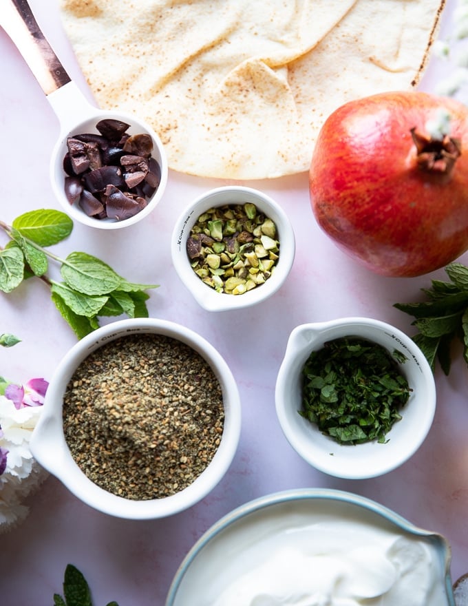 toppings for labneh dip including zaatar, olives, mint, pomegranates, pistachios and olive oil