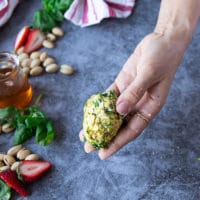 A hand holding the strawberries coated in pistachios