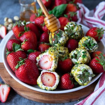 sliced up strawberries with goat cheese showing the inside texture and a honey drizzle over the top