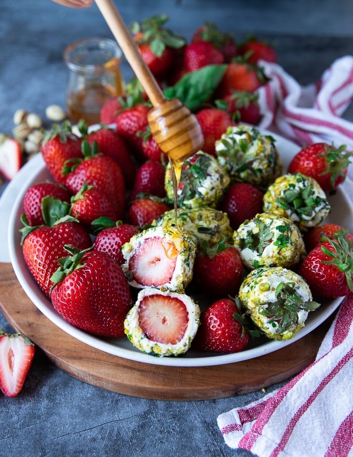 sliced up strawberries with goat cheese showing the inside texture and a honey drizzle over the top