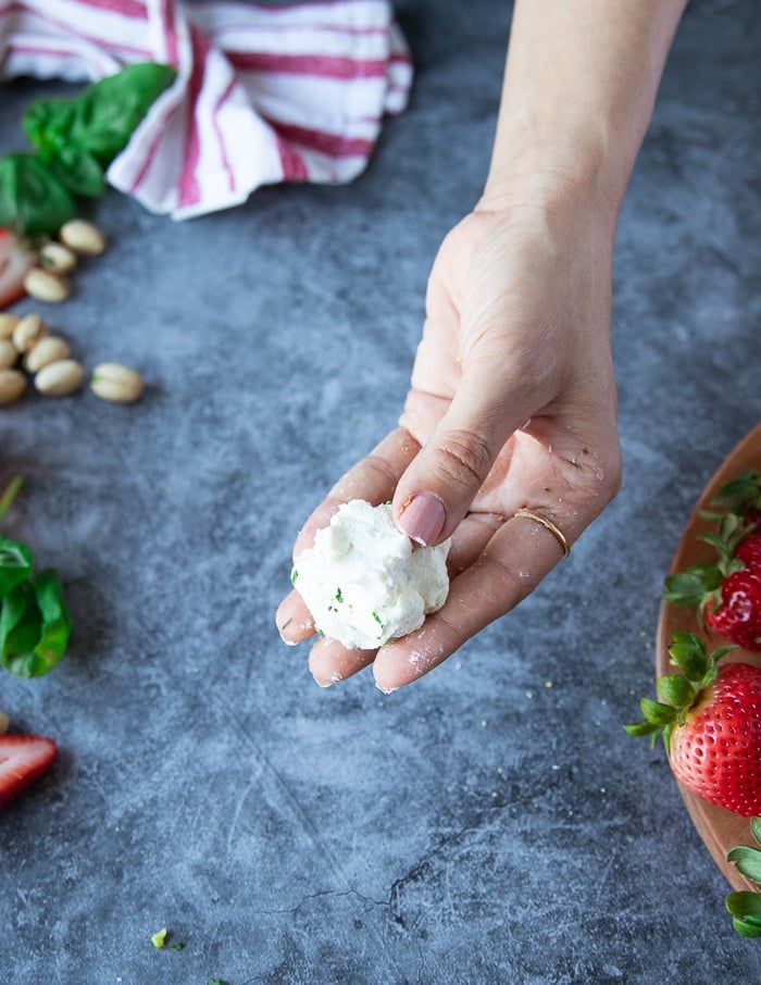 A hand holding a ball of goat cheese