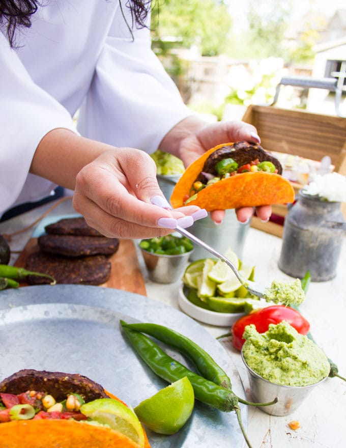 Topping the burger in the taco shell with some guacamole