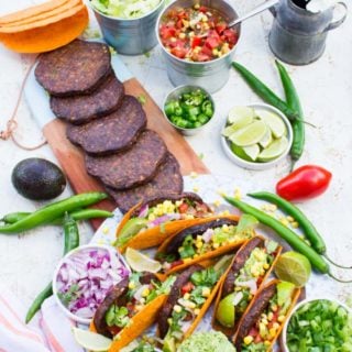 Top view of A burger taco party with all the ingredients taco shells, grilled burgers, guacamole, salsa, chopped jalapenos and chopped onions