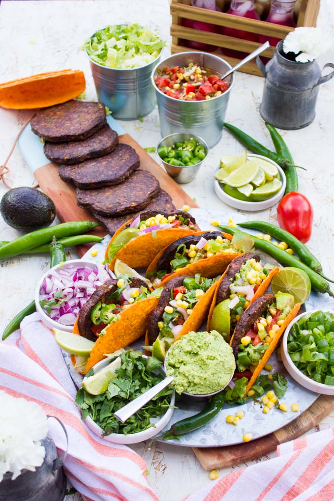 side angle view Top view of A burger taco party with all the ingredients taco shells, grilled burgers, guacamole, salsa, chopped jalapenos and chopped onions