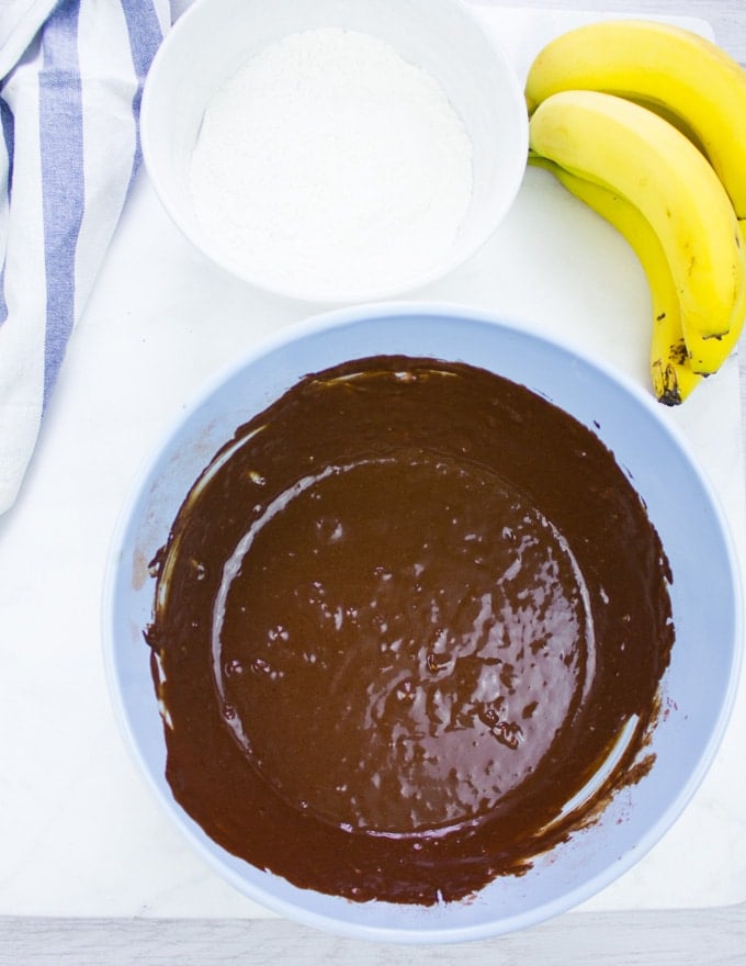 two bowls, one for dry ingredients and the other for the wet ingredients and some bananas ready to make the banana chocolate chip.