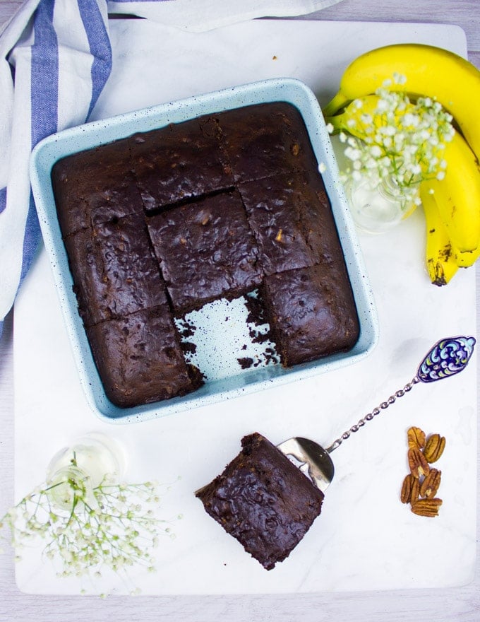 Top View of Banana Chocolate Chip cake with one slice removed from the pan and some bananas around the chocolate banana bread