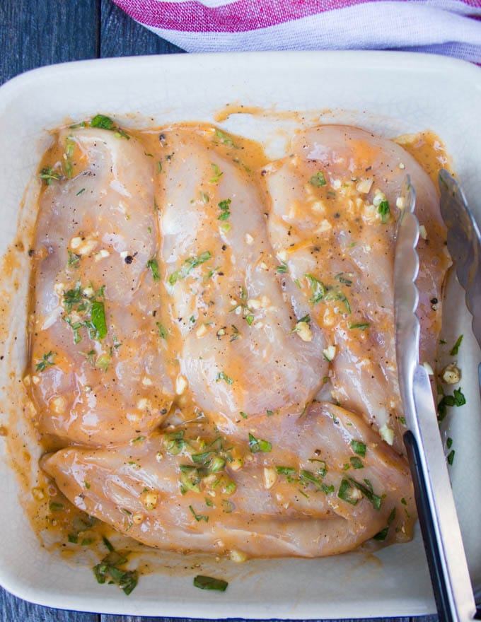 marinated raw chicken breasts in a deep dish ready to be grilled