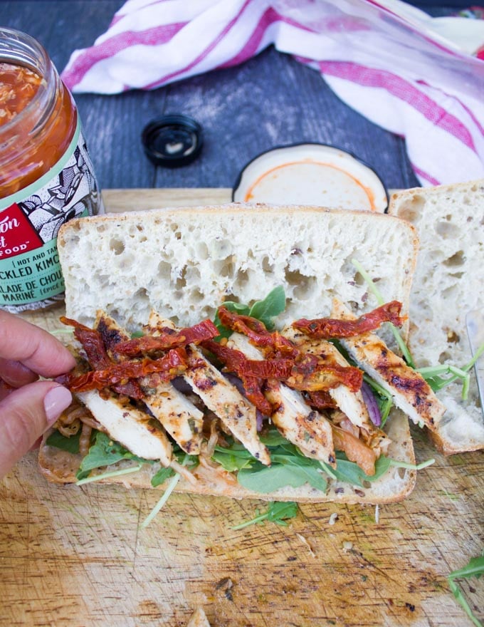 Assembling the chicken sandwich with chicken and sun dried tomatoes