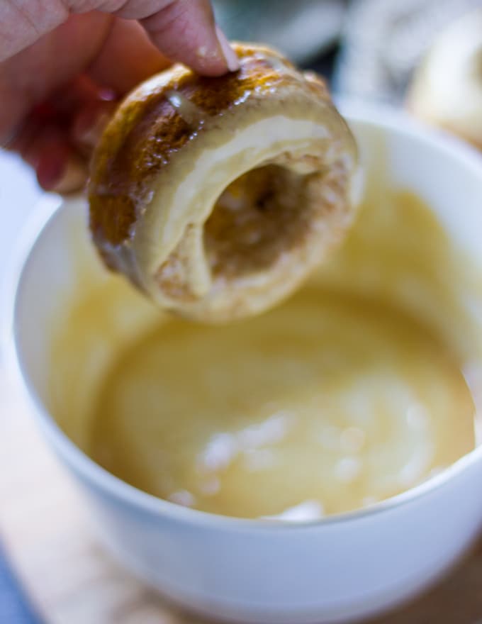 A hand dipping the baked donut into the espresso glaze