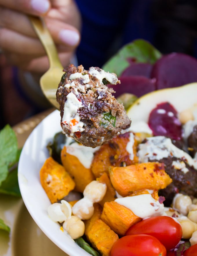 A fork holding a bitten piece of lamb meatball