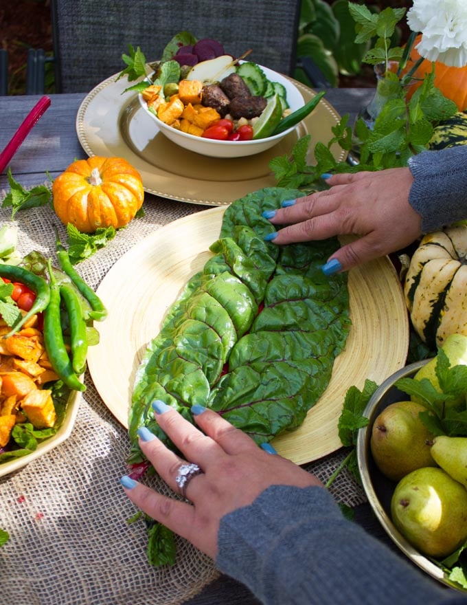 An empty bowl and a hand putting a layer of swiss chard over it