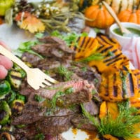 A fork holding a piece of grilled steak with a drizzle of dill sauce