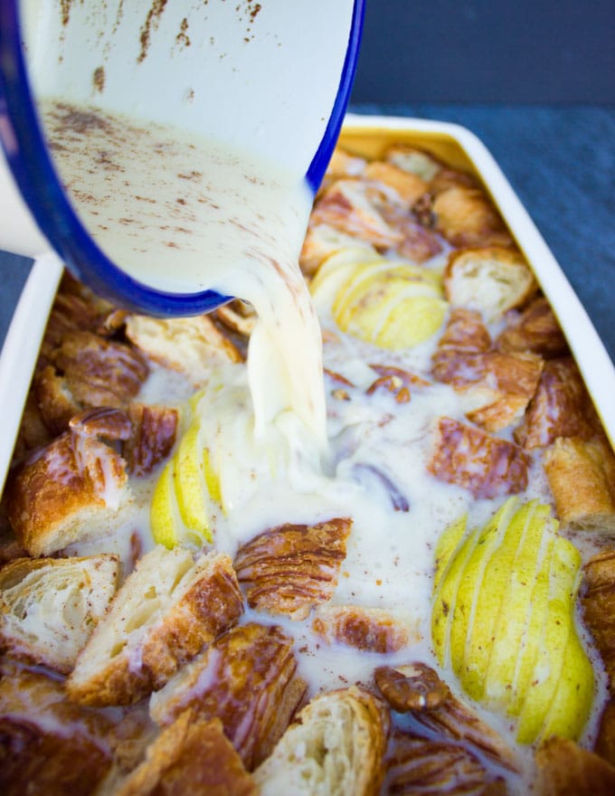 pouring a cinnamon custard over the croissant cubes and sliced pears