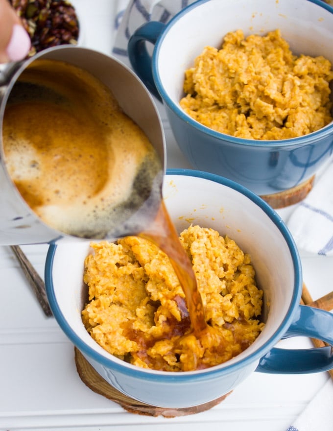 Hot espresso being poured over the pumpkin spice oatmeal in a cup.