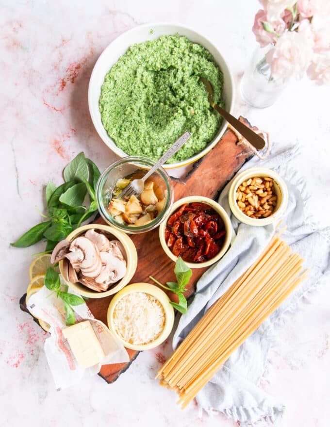 Ingredients to make broccoli pesto pasta on a large board in small bowls