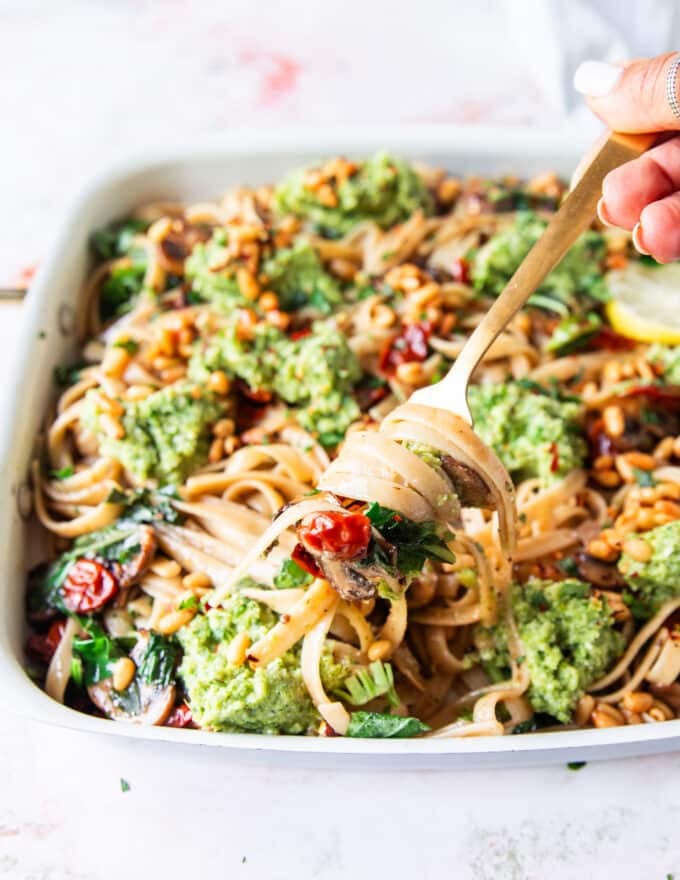 A fork pulling the broccoli pesto pasta stretching and showing the beautiful dish