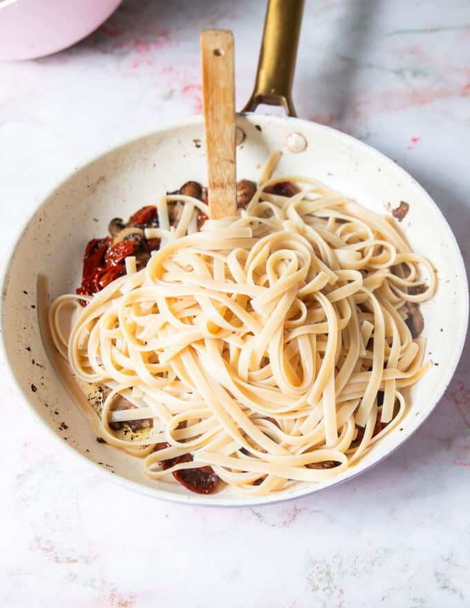 The cooked pasta and pasta water is added to the sauce pan