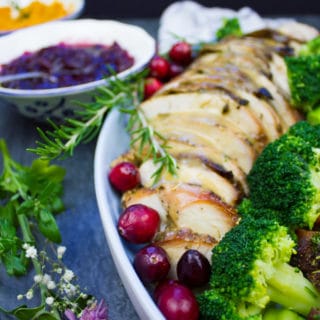 A platter showing close up of some slices of roast turkey, a flower and some broccoli