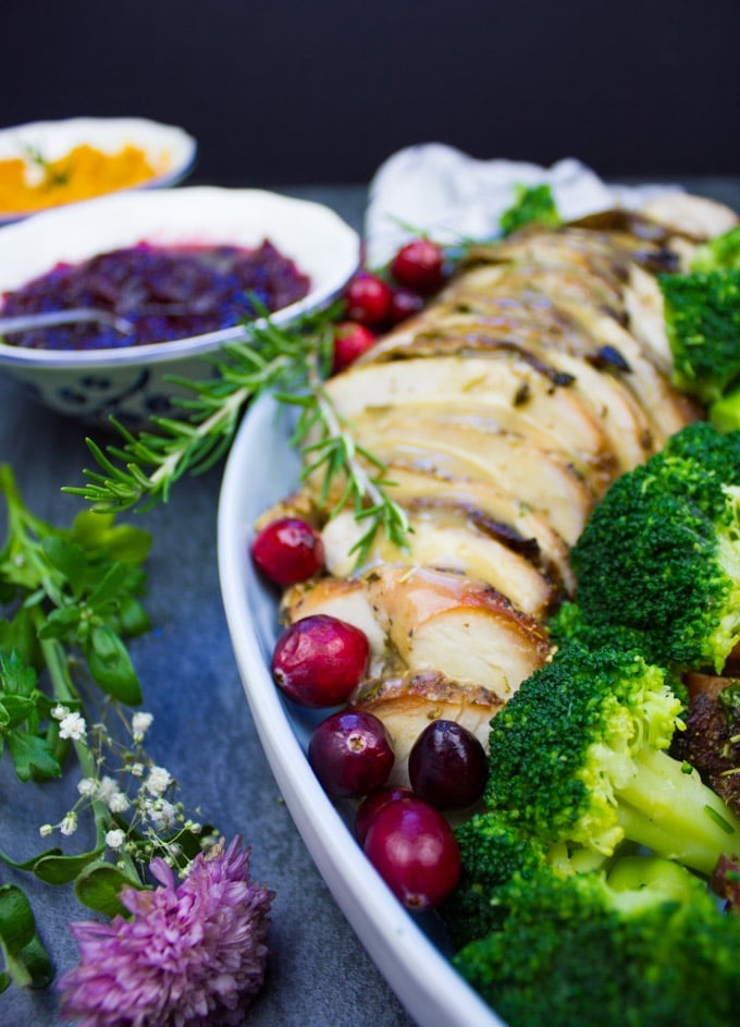 A platter showing close up of some slices of roast turkey, a flower and some broccoli 
