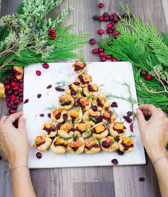 A hand serving a marble of a fully loaded easy appetizer festive tree shaped pastries for a party or a crowd.