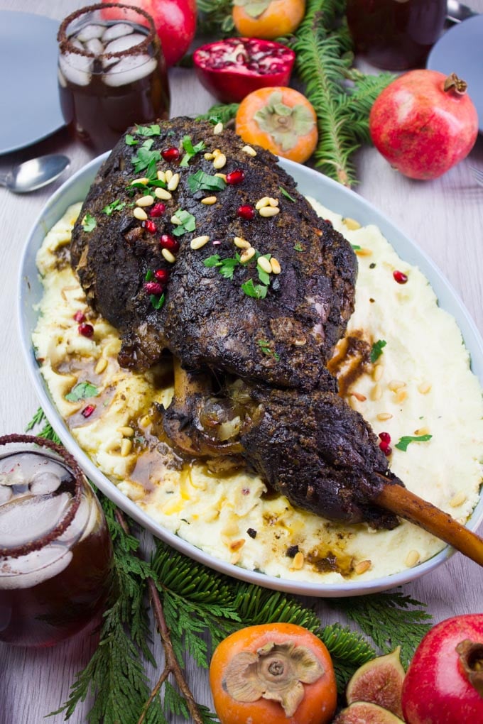 The main dish of a whole leg of lamb roasted over mashed potatoes on a serving table