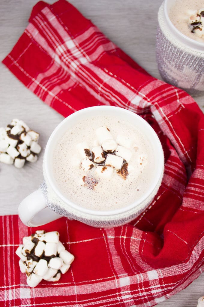 A single cup of hot chocolate surrounded by a red towel and topped with OREO cookie balls.