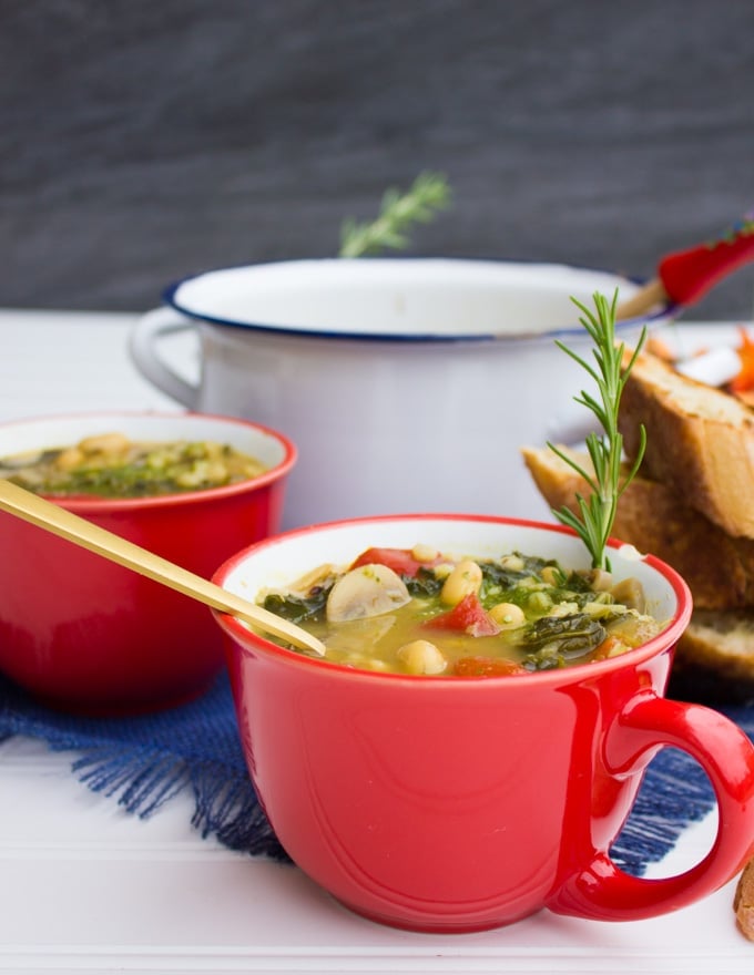 A bowl of soup with a spoon and a big pot of white bean soup at the back