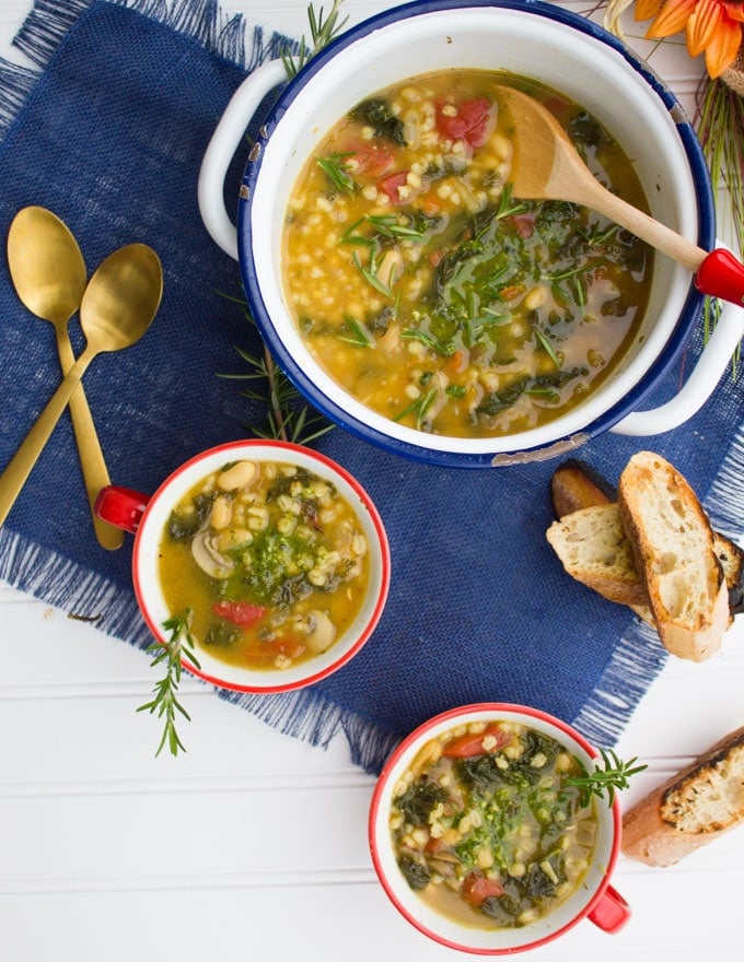 Top view of three soup bowls and spoons with some crunchy bread over a mat.