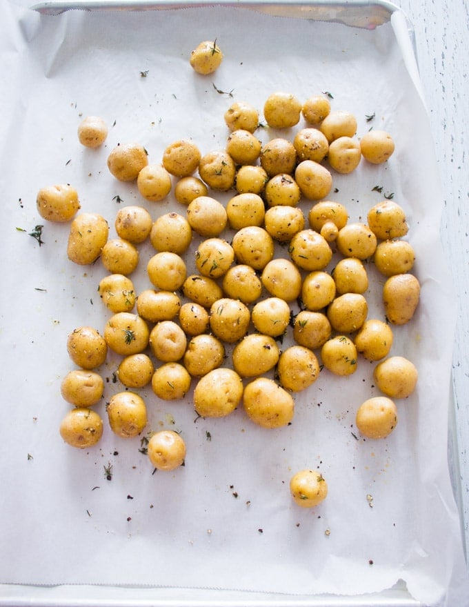 A baking sheet with potatoes seasoned ready to be roasted