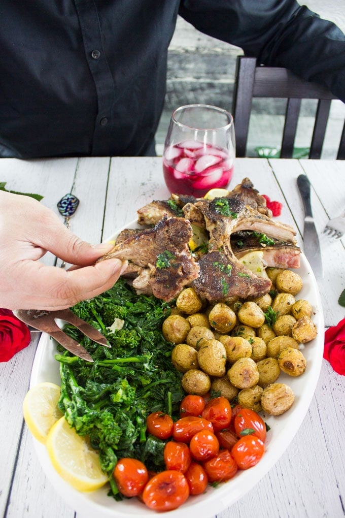 A hand holding a bitten piece of lamb chops showing the succulent lamb