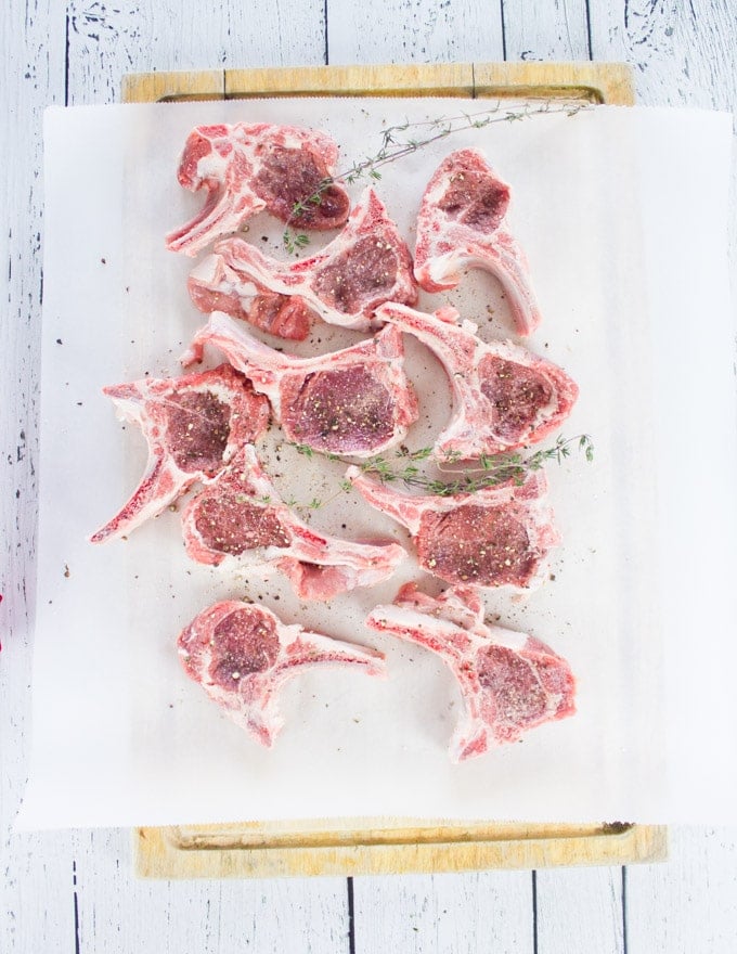 Raw seasoned lamb chops on a parchment paper ready to be cooked