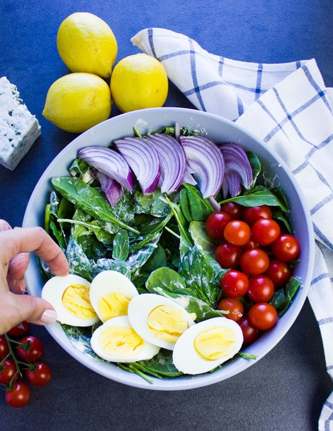 A hand arranging hard boiled eggs for a smoked salmon salad.