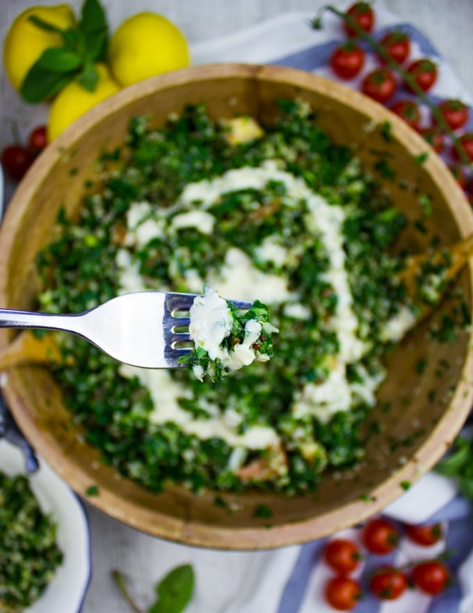 A fork scooping some tabouleh salad with tahini dressing over the bowl of tabouli