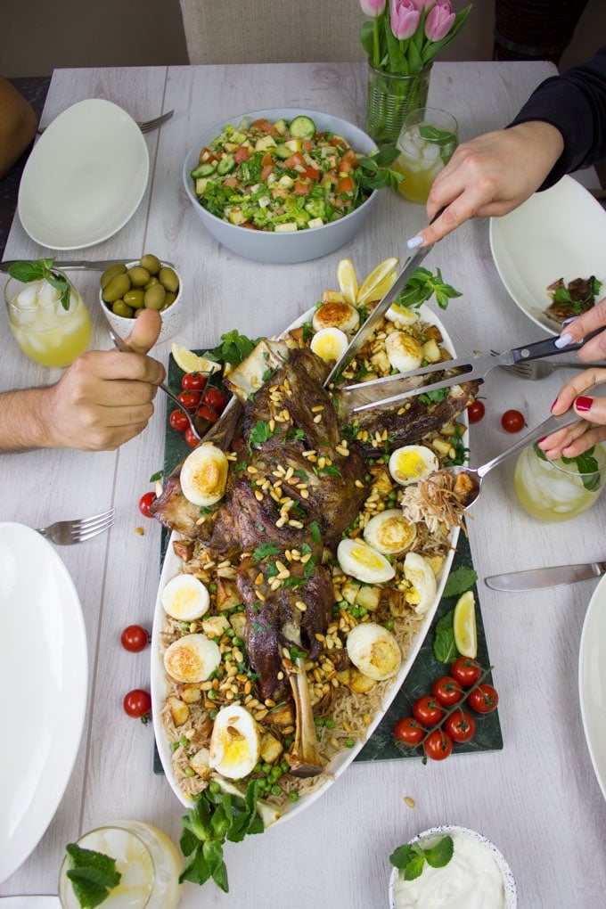 Hands sercing and cutting away the lamb, the rice and salad for easter dinner.