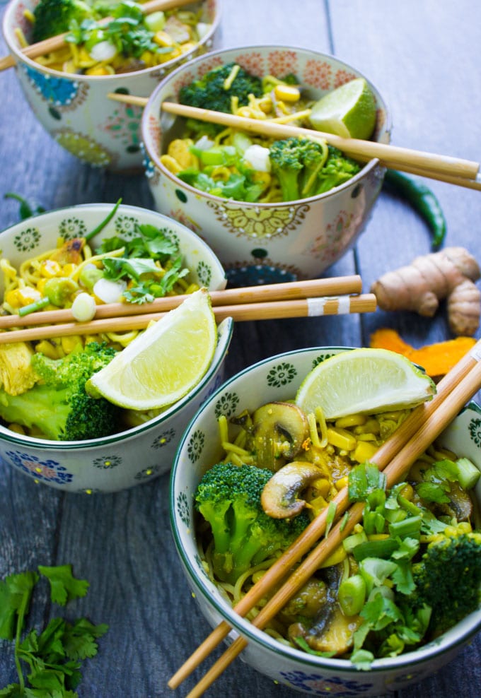 3 spicy ramen bowls with chopsticks and lime wedges, broccoli and mushrooms