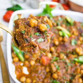 A spoon holding up a roast lamb chop with chickpeas showing close up of the lamb