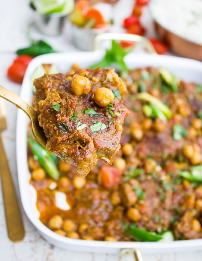 A spoon holding up a roast lamb chop with chickpeas showing close up of the lamb