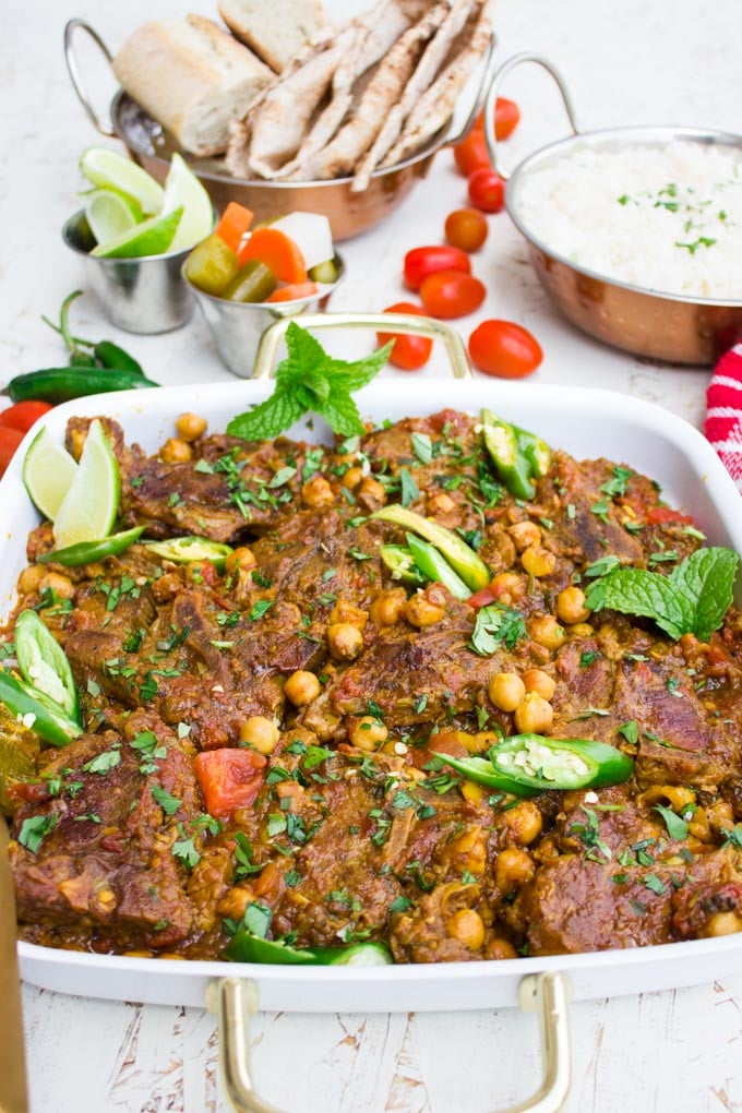 Side view of roast lamb and chickpeas and a plate of pita bread, rice on the side to enjoy.