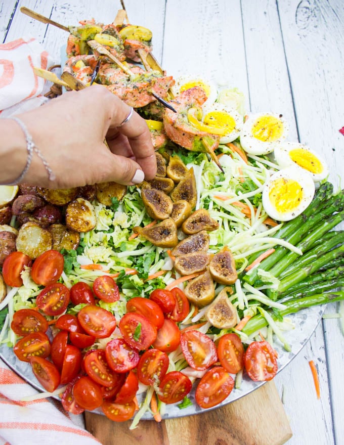 A hand adding the figs over the salad