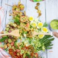 two hands holding a serving spoon and serving salmon salad